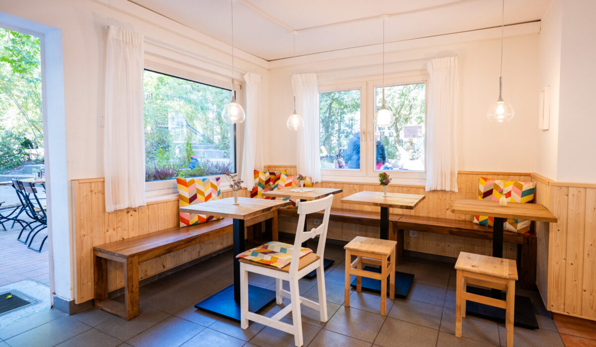 Innenraum von Frau Meis Eis · Café mit mehren Tischen und Stühlen und einer hölzernen Eckbank