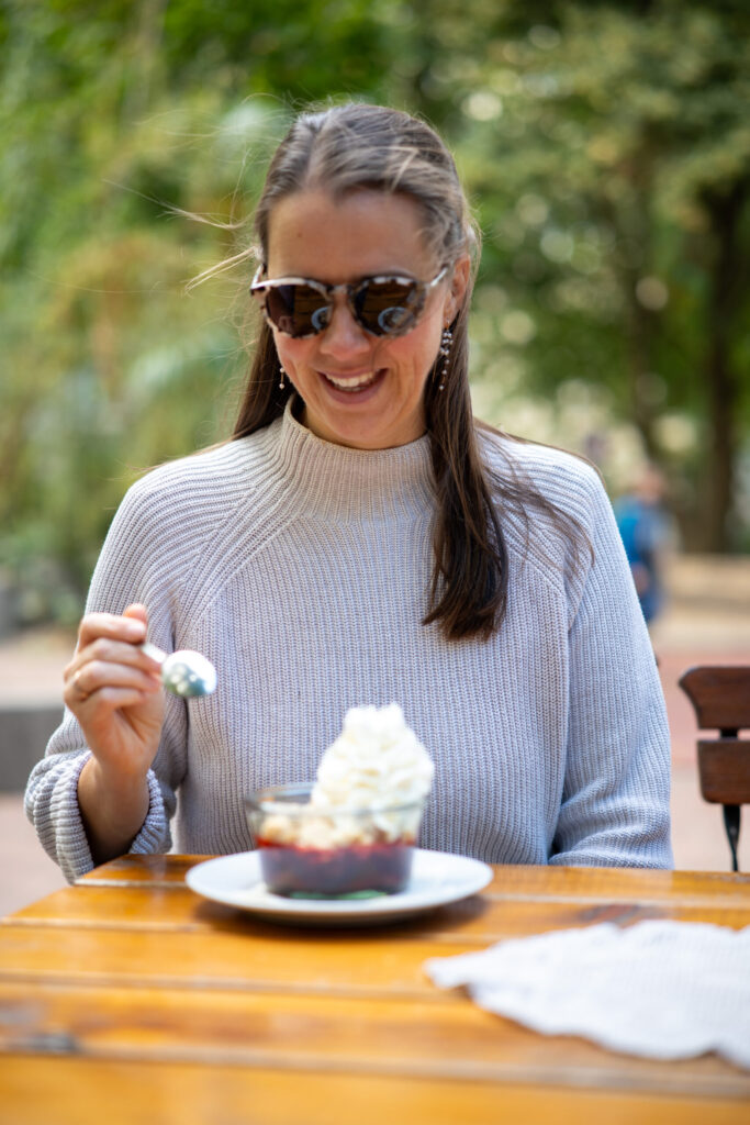 Eine Frau isst von einem Crumble mit Sahne