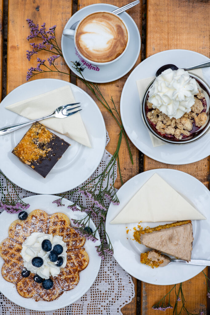 Gedeckte Kaffetafel mit Waffel, Kuchen und Kaffe auf einem Holztisch