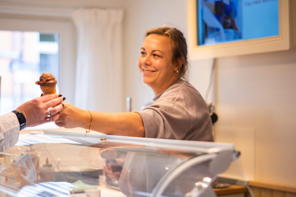 Eine Frau reicht eine Kugel Schokoladeneis über die Eistheke